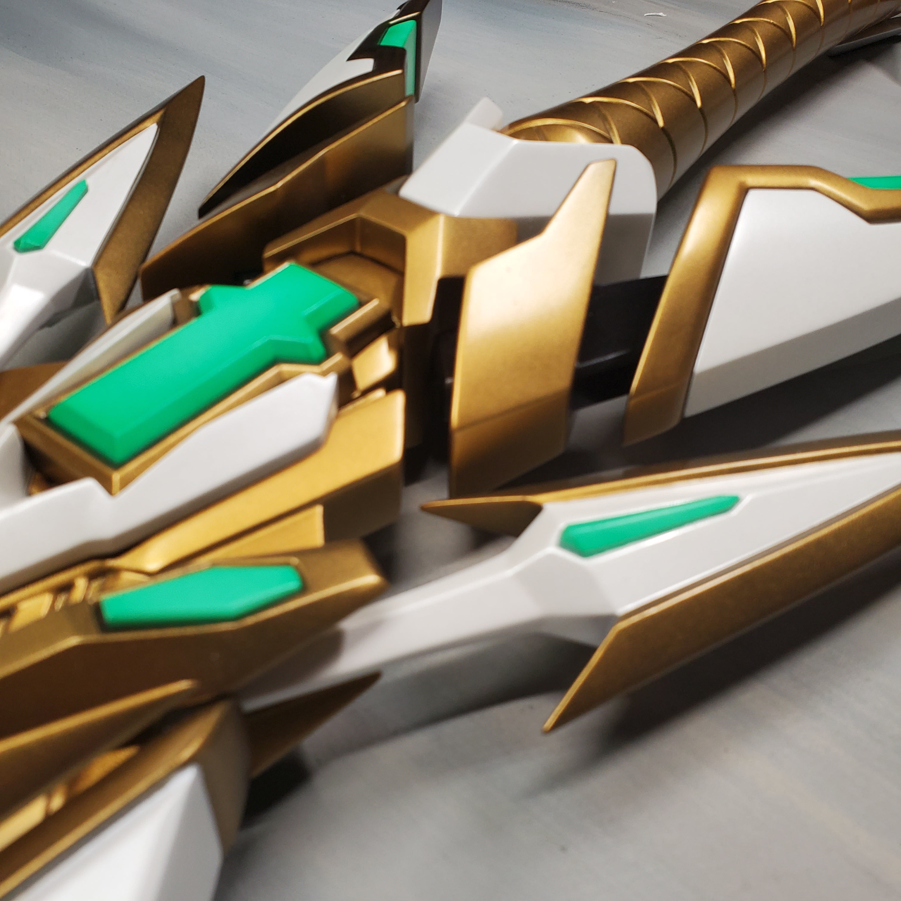 Close-up of a gold and green mechanical design on a gray background