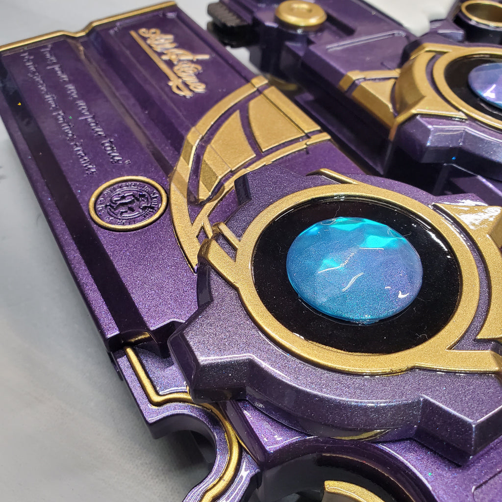 Close-up of a purple and gold mechanical device with a glowing blue center.