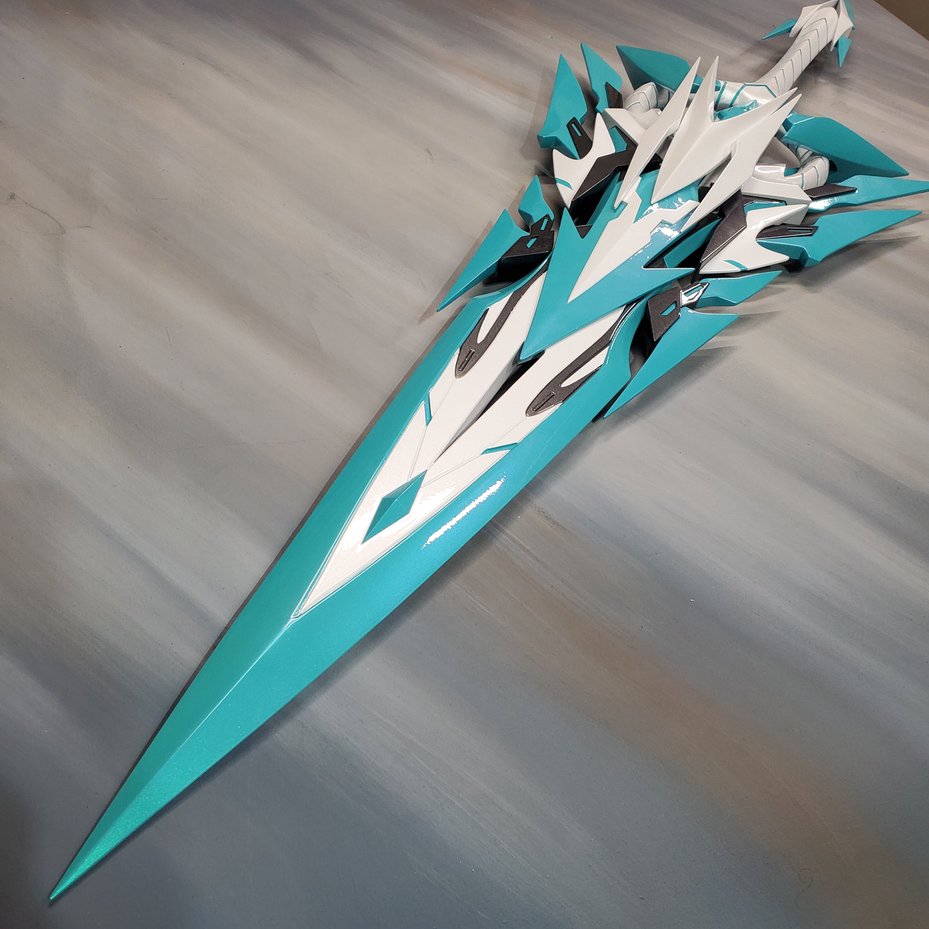 Teal and white fantasy sword on a gray background