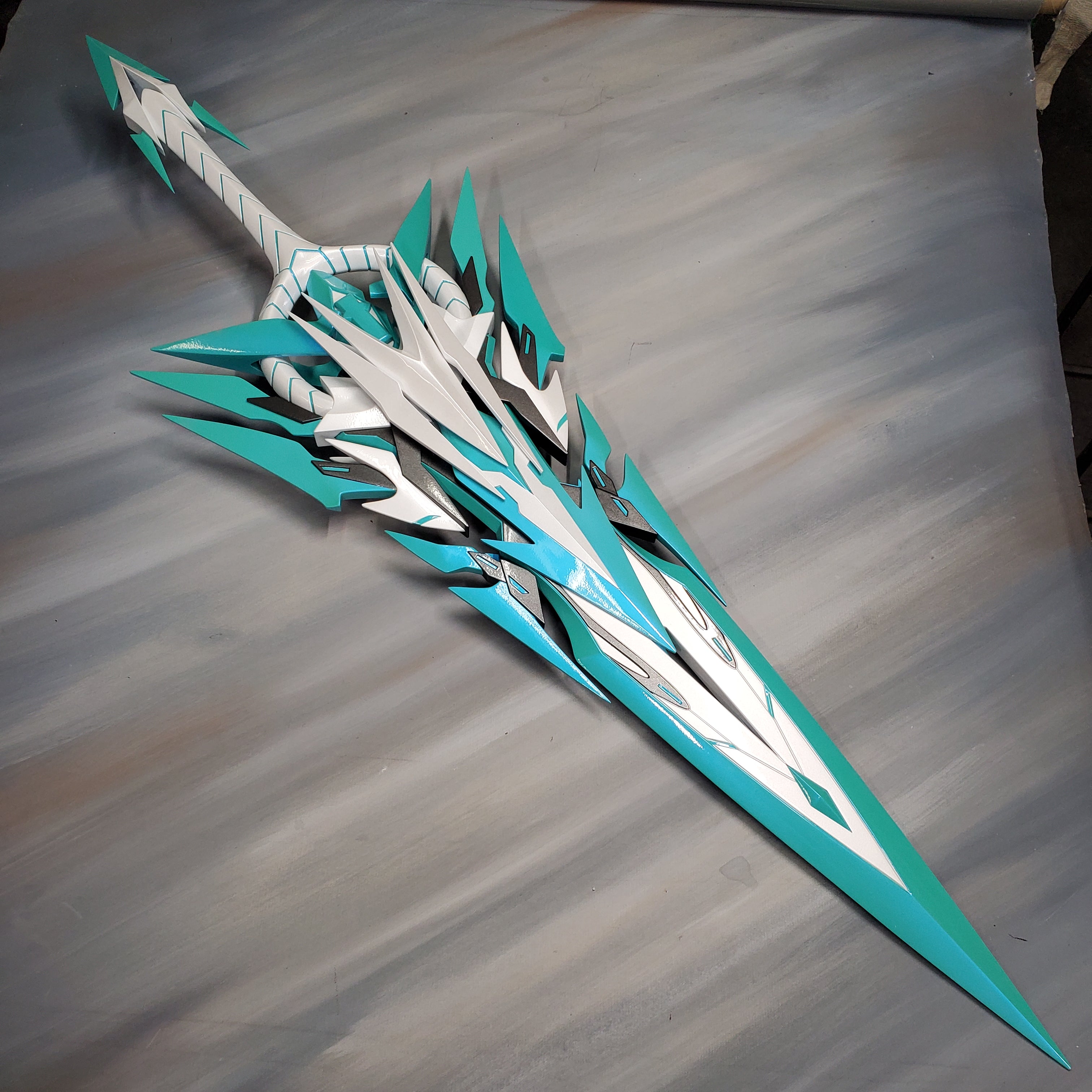 Teal and white sword-like object on a wooden surface