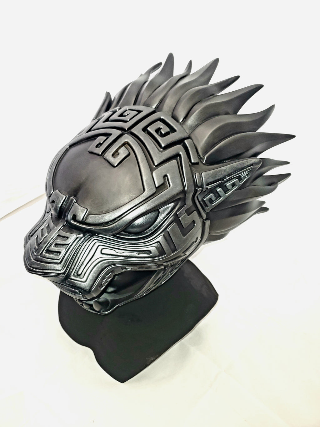 Metallic dragon helmet on a stand with a white background