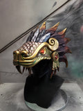 Hand‑sculpted Quetzalcóatl warrior mask with metallic gold, green, and violet detailing displayed on a black mannequin head