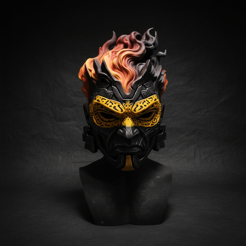 A fantasy-style sculpted mask bust displayed on a dark stand in a workshop setting. The mask features a black base with ornate gold facial detailing and vivid orange-red flames rising from the top.
