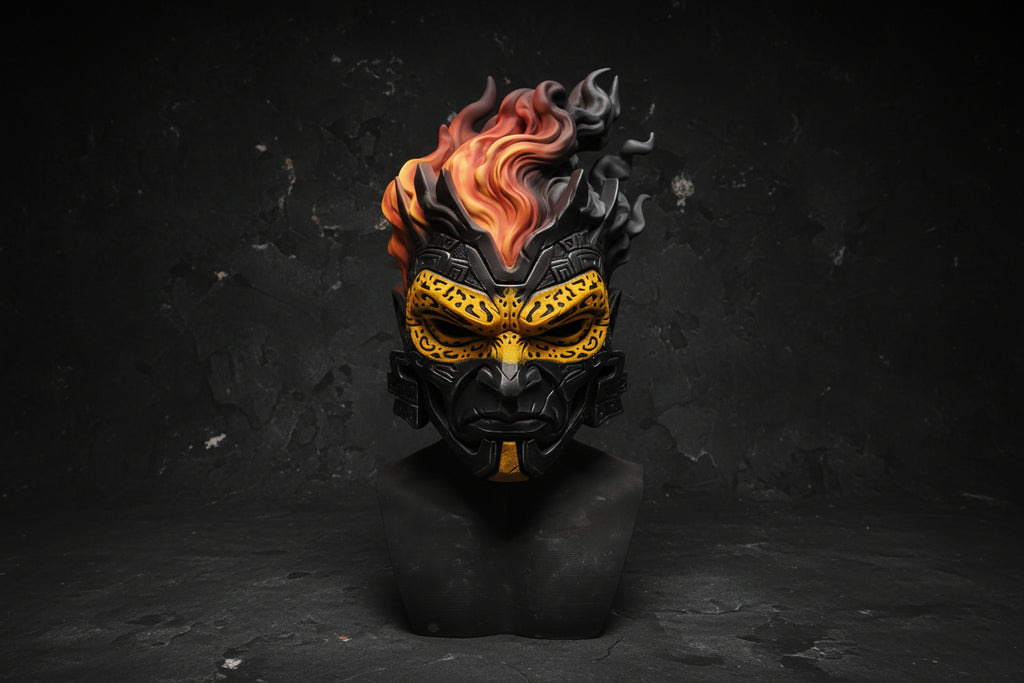 A detailed fantasy mask sculpture on a black bust, featuring a black base with yellow patterns and orange-red flames on top, set against a gray backdrop.