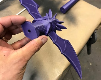 Purple dragon-shaped object held by a hand on a neutral background