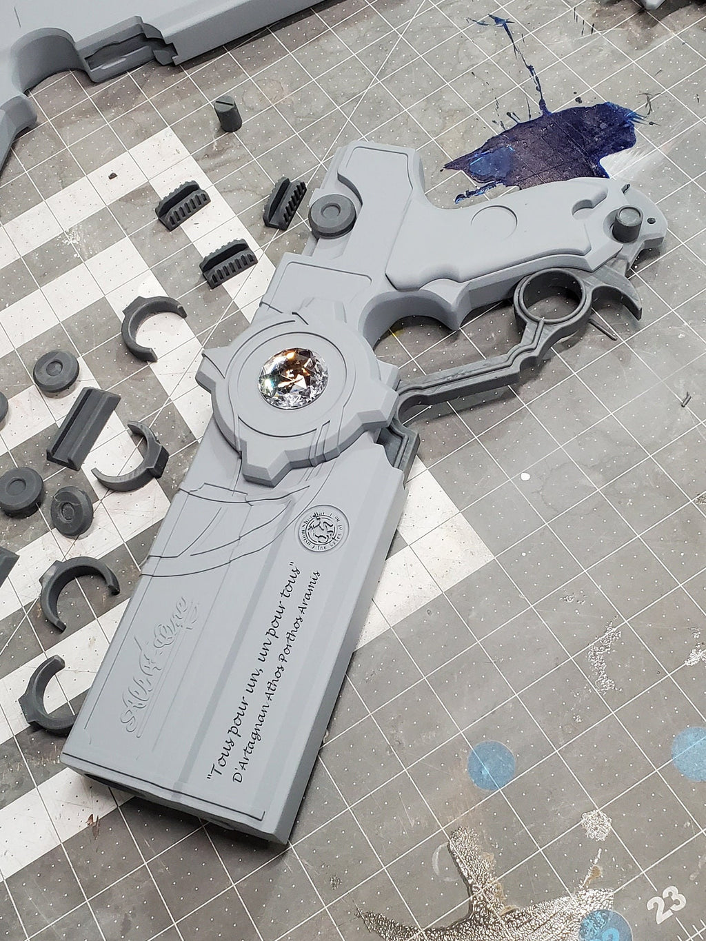 Gray fidget spinner on a checkered surface with scattered parts