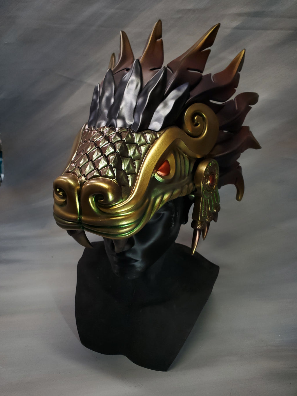 Decorative mask with gold, silver, and bronze colors on a plain background