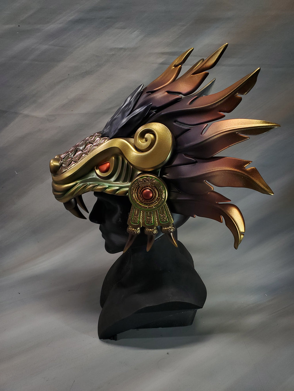 Decorative headpiece with feathers and gold accents on a gray background