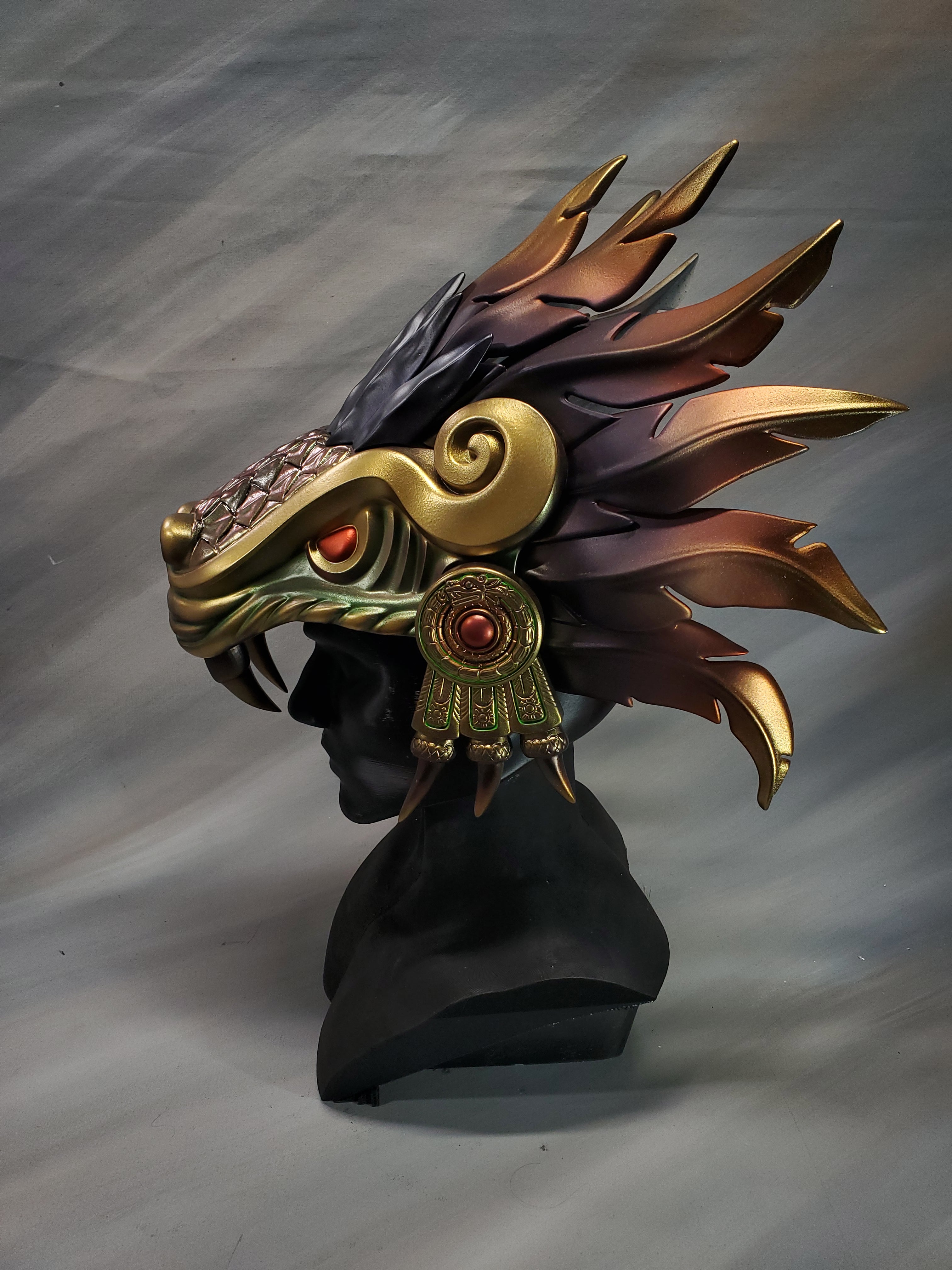 Decorative headpiece with feathers and gold accents on a gray background