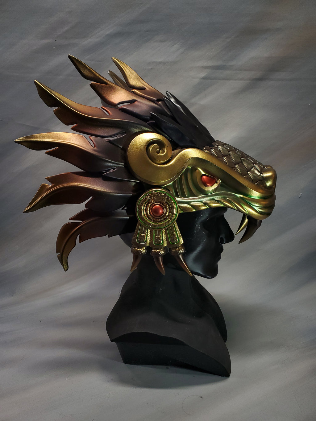 Decorative headpiece with gold and black design on a gray background