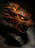 Ornate mask with orange and black design on a dark background