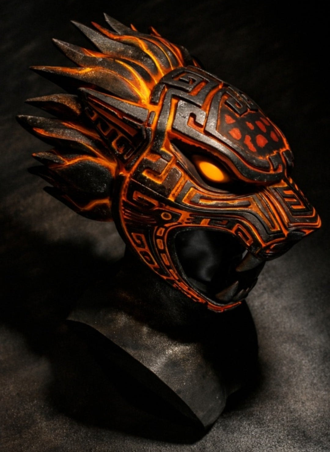 Ornate mask with orange and black design on a dark background
