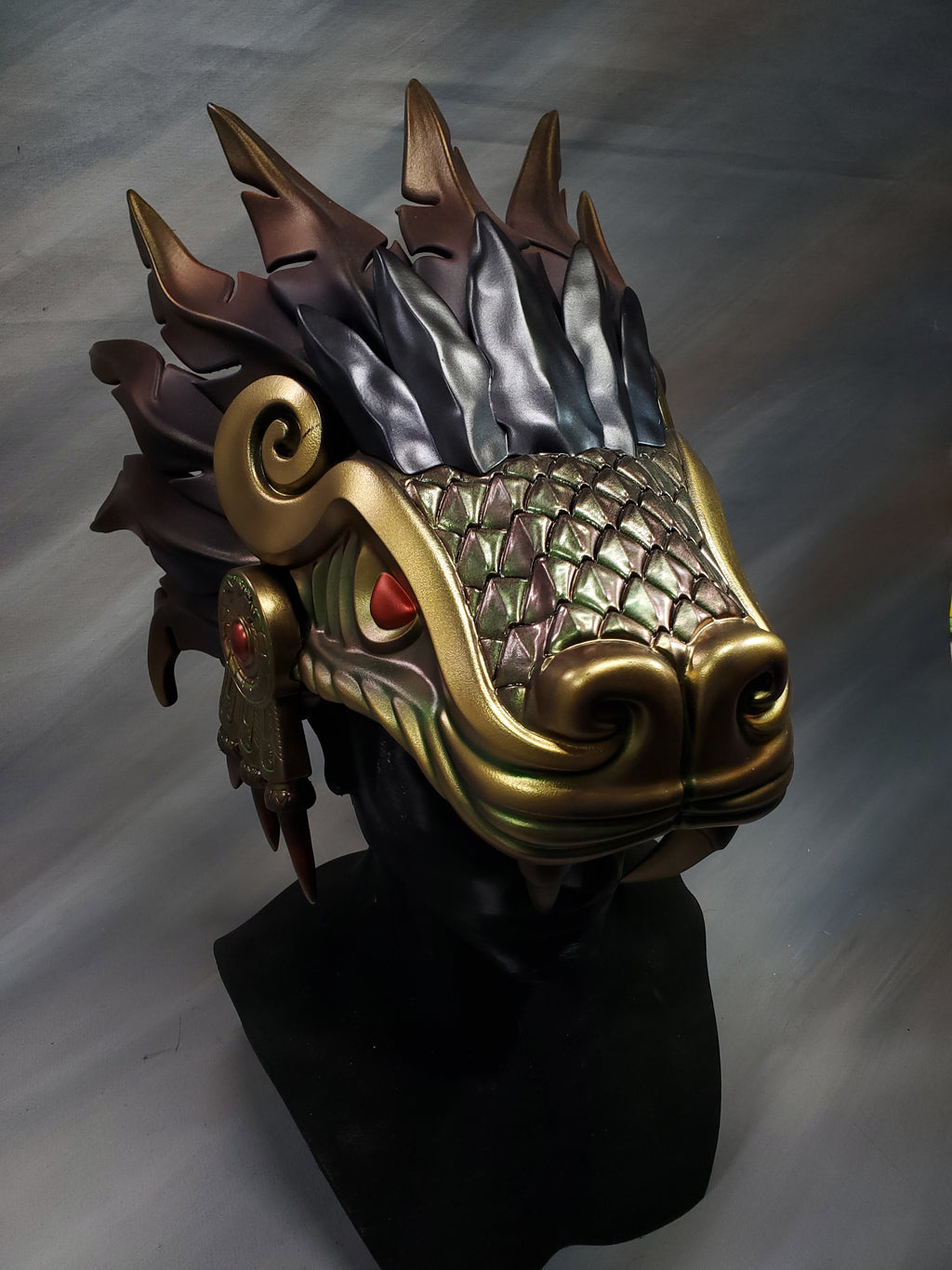 Decorative mask with gold and black design on a white background