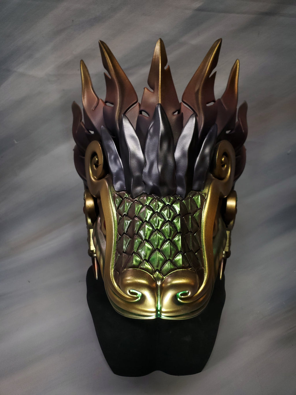 Dragon-like mask with metallic accents on a gray background