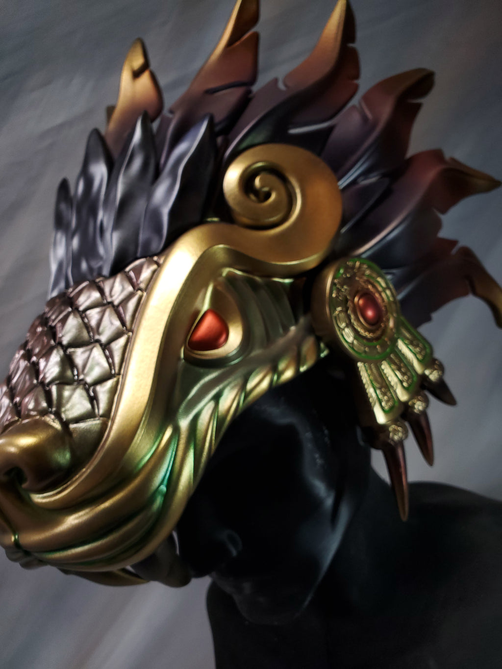 Decorative headpiece with gold, bronze, and red details on a plain background