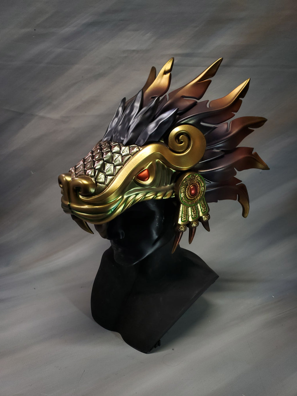 Decorative headpiece with gold and black design on a gray background